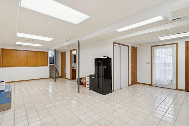 1801 Payton Ave, Des Moines, IA 50315 - basement featuring stairway, baseboards, light tile patterned flooring, and a paneled ceiling