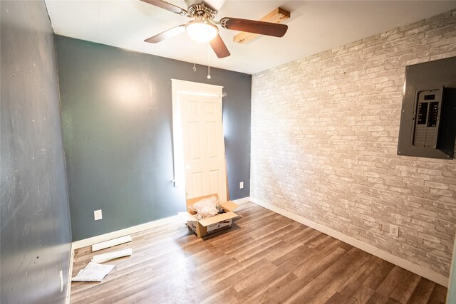 3518 Easton Blvd, Des Moines, IA 50317 - spare room with electric panel, ceiling fan, wood finished floors, brick wall, and baseboards