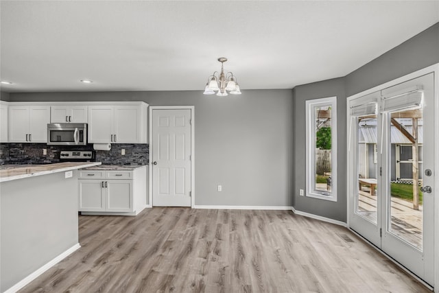 904 SE Little Beaver Dr, Grimes, IA 50111 - kitchen with stainless steel microwave, light wood-type flooring, white cabinetry, a chandelier, and backsplash