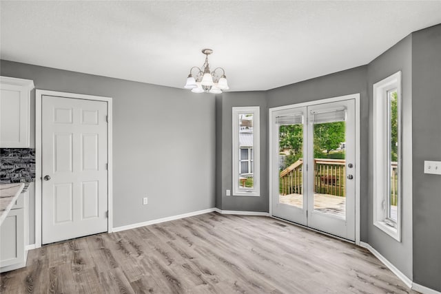 904 SE Little Beaver Dr, Grimes, IA 50111 - unfurnished dining area featuring a chandelier, light wood-style flooring, and baseboards