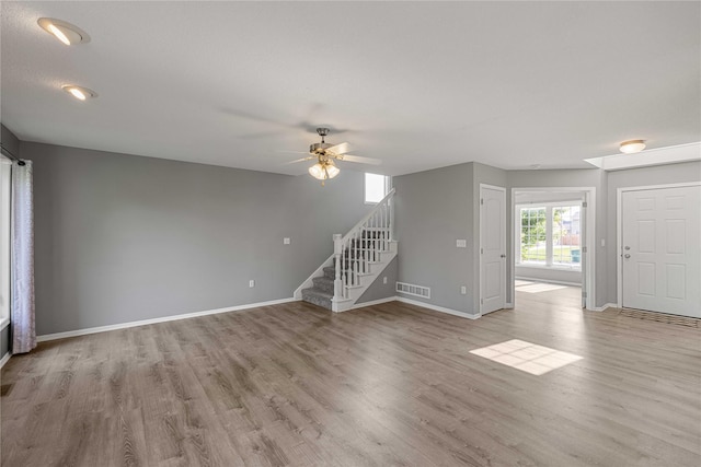 904 SE Little Beaver Dr, Grimes, IA 50111 - unfurnished living room featuring stairway, wood finished floors, a ceiling fan, and baseboards