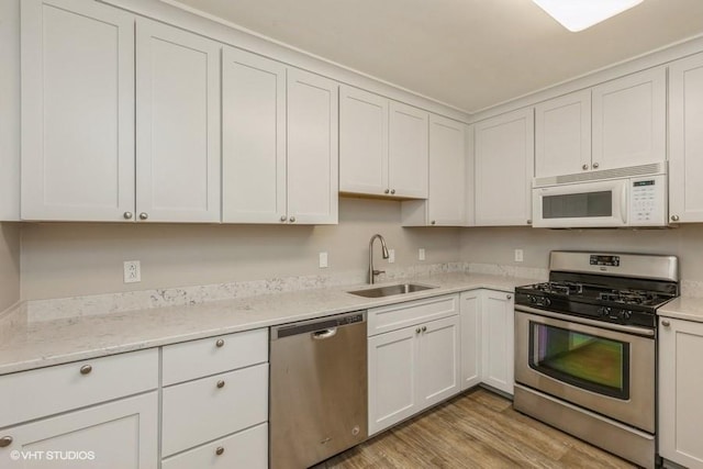 6445 Center St, Windsor Heights, IA 50324 - kitchen with stainless steel appliances, a sink, light wood-type flooring, and white cabinetry