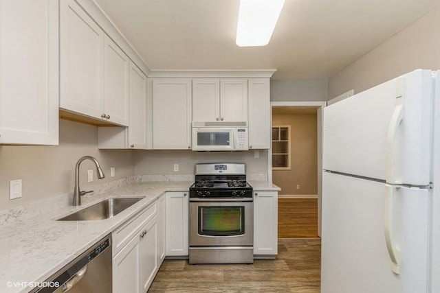 6445 Center St, Windsor Heights, IA 50324 - kitchen with appliances with stainless steel finishes, a sink, light wood finished floors, white cabinetry, and light stone counters