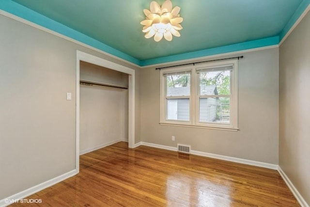 6445 Center St, Windsor Heights, IA 50324 - unfurnished bedroom featuring a chandelier, wood finished floors, baseboards, and a closet
