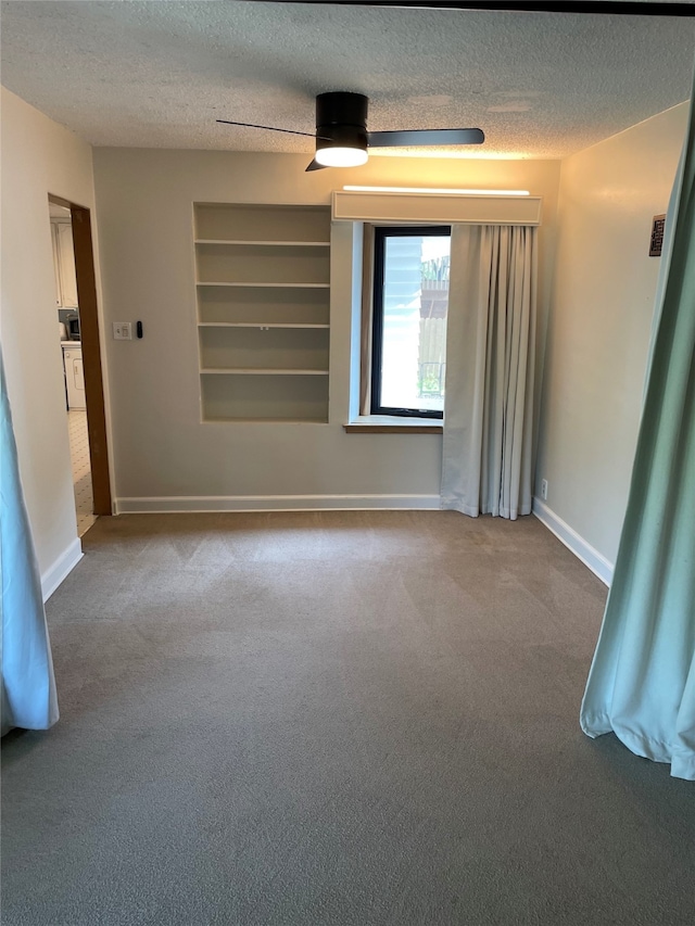 1620 Broad St, Grinnell, IA 50112 - empty room with a textured ceiling, carpet, built in shelves, and baseboards