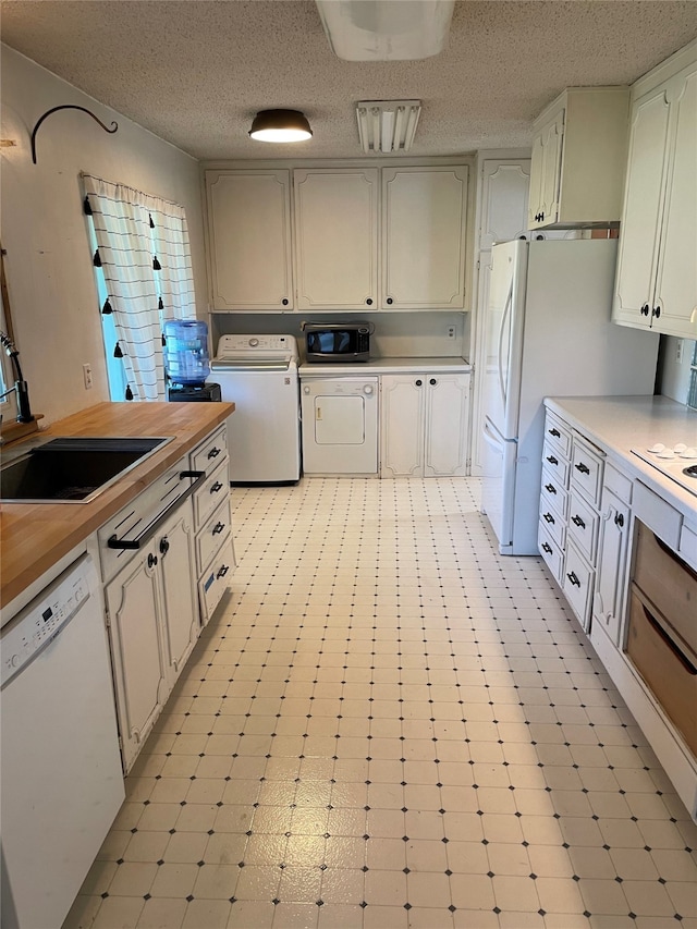 1620 Broad St, Grinnell, IA 50112 - kitchen featuring washer / dryer, white appliances, a sink, wooden counters, and a textured ceiling