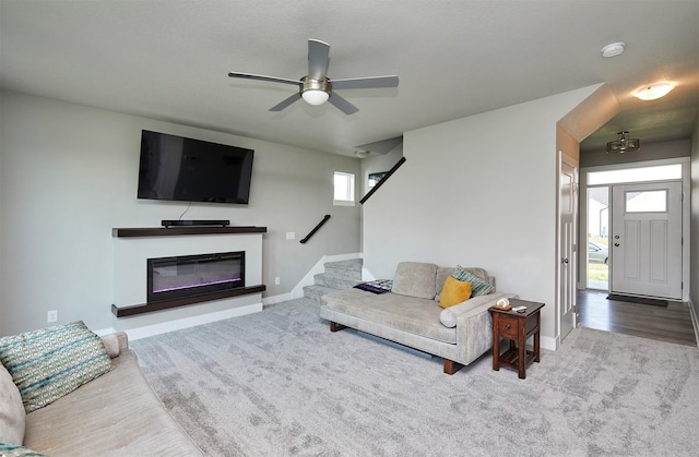 2930 Kestrel St, Norwalk, IA 50211 - living room featuring carpet floors, a ceiling fan, stairs, and a glass covered fireplace