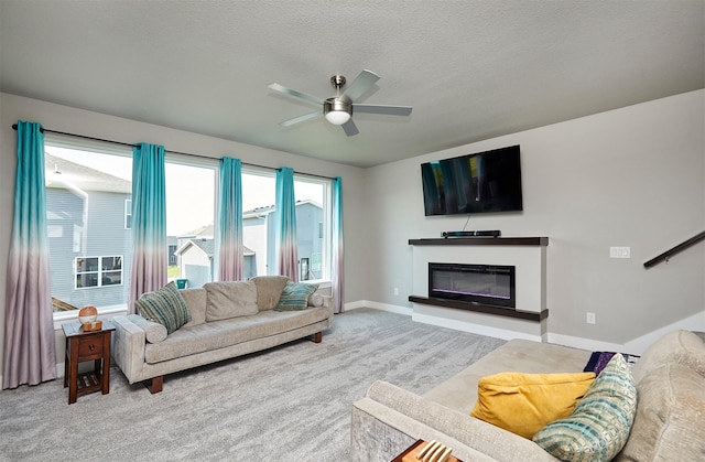 2930 Kestrel St, Norwalk, IA 50211 - carpeted living area featuring a ceiling fan, a glass covered fireplace, and a textured ceiling