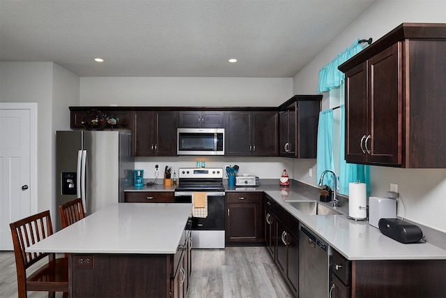 2930 Kestrel St, Norwalk, IA 50211 - kitchen with appliances with stainless steel finishes, light wood-style flooring, dark brown cabinetry, a kitchen island, and recessed lighting