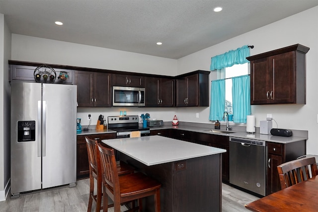 2930 Kestrel St, Norwalk, IA 50211 - kitchen with stainless steel appliances, light wood finished floors, dark brown cabinets, a kitchen island, and recessed lighting