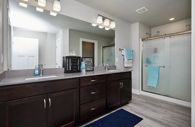 2930 Kestrel St, Norwalk, IA 50211 - bathroom featuring a stall shower, double vanity, wood finished floors, and recessed lighting