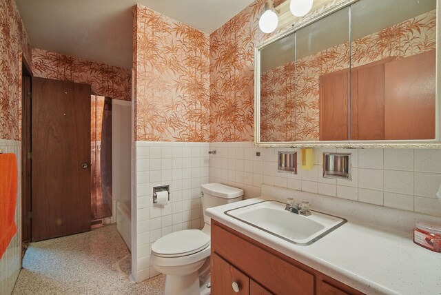 4500 100th St, Urbandale, IA 50322 - bathroom featuring wallpapered walls, a wainscoted wall, vanity, and tile walls