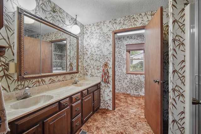 4500 100th St, Urbandale, IA 50322 - bathroom with wallpapered walls, a textured ceiling, and double vanity
