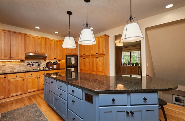 2556 NW 162nd St, Clive, IA 50325 - kitchen with under cabinet range hood, a center island, light wood-style floors, black electric stovetop, and decorative backsplash