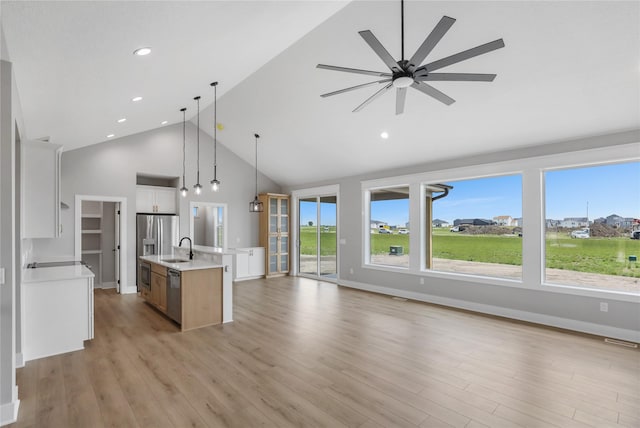 1201 Lakeview Cir NW, Bondurant, IA 50035 - kitchen featuring high vaulted ceiling, stainless steel appliances, light countertops, a sink, and open floor plan