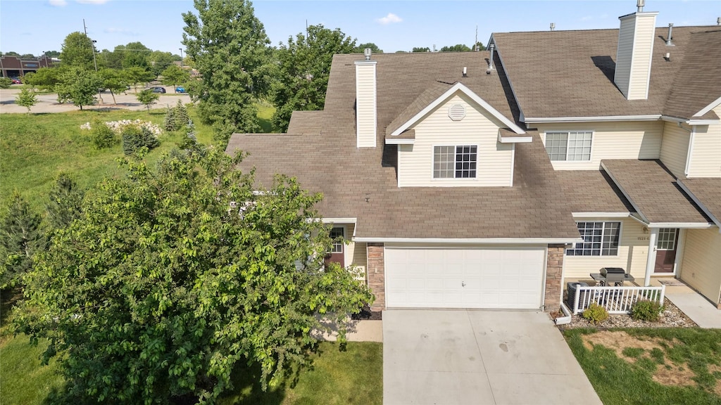 1521 SE Delaware Ave Unit 5, Ankeny, IA 50021 - view of front of house featuring a chimney, concrete driveway, a garage, and roof with shingles