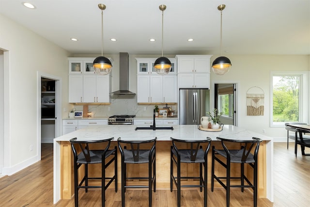 1030 Harrington Way, Waukee, IA 50263 - kitchen featuring wall chimney exhaust hood, appliances with stainless steel finishes, light wood-style floors, a kitchen island with sink, and recessed lighting