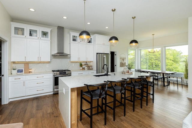 1030 Harrington Way, Waukee, IA 50263 - kitchen with appliances with stainless steel finishes, wall chimney exhaust hood, a large island with sink, dark wood finished floors, and recessed lighting