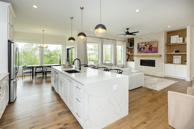1030 Harrington Way, Waukee, IA 50263 - kitchen featuring freestanding refrigerator, a stone fireplace, healthy amount of natural light, white cabinets, and recessed lighting