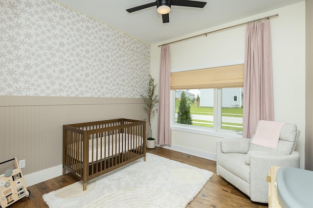 1030 Harrington Way, Waukee, IA 50263 - bedroom with wallpapered walls, a nursery area, wainscoting, and wood finished floors