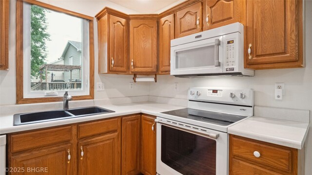 1105 E Henderson Pl, Indianola, IA 50125 - kitchen featuring white appliances, a sink, brown cabinets, and light countertops