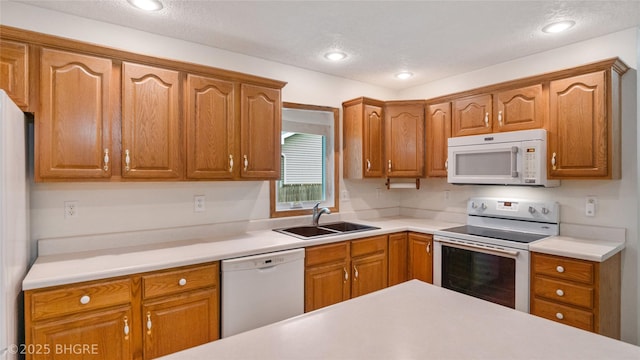 1105 E Henderson Pl, Indianola, IA 50125 - kitchen featuring white appliances, a sink, light countertops, brown cabinets, and recessed lighting
