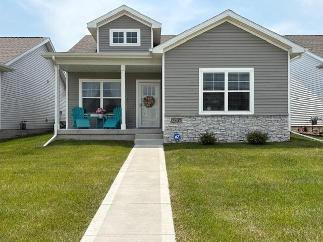 2807 NW 31st St, Ankeny, IA 50023 - view of front facade featuring a porch, a front lawn, stone siding, and a shingled roof
