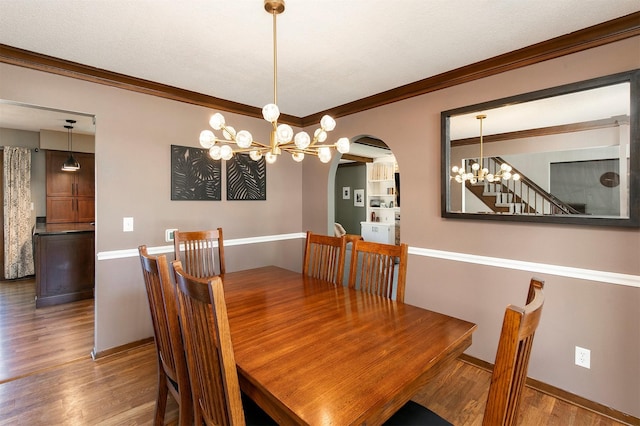 9873 Colby Ave, Clive, IA 50325 - dining room with a chandelier, wood finished floors, ornamental molding, baseboards, and arched walkways