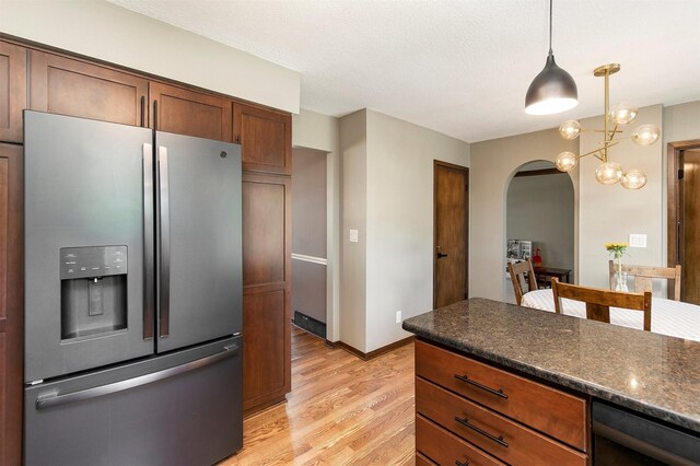 9873 Colby Ave, Clive, IA 50325 - kitchen with stainless steel fridge, arched walkways, light wood finished floors, and dark countertops