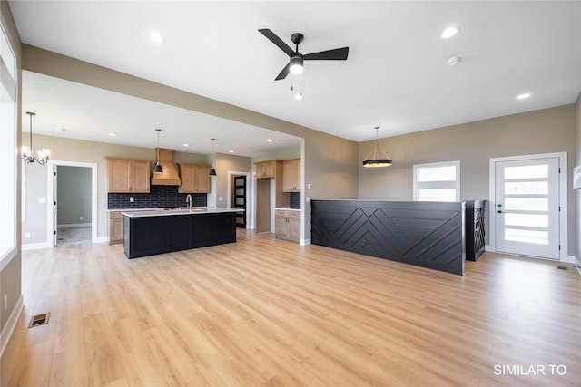 610 Ellis Cir, Adel, IA 50003 - unfurnished living room featuring light wood finished floors, ceiling fan, recessed lighting, a sink, and a chandelier