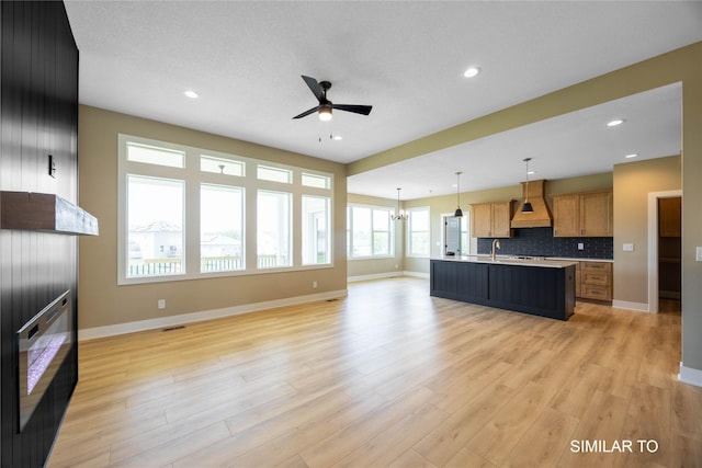 610 Ellis Cir, Adel, IA 50003 - unfurnished living room with a ceiling fan, light wood-style floors, baseboards, recessed lighting, and a sink