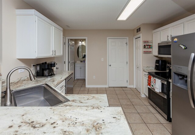 601 Orchard Hills Dr Unit 5011, Norwalk, IA 50211 - kitchen with stainless steel appliances, a sink, white cabinetry, light tile patterned floors, and baseboards