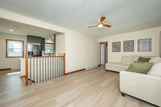 2607 E 39th St, Des Moines, IA 50317 - living room featuring light wood-style floors, a ceiling fan, and baseboards