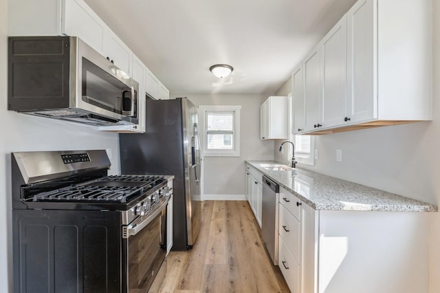 3811 E 30th St, Des Moines, IA 50317 - kitchen with stainless steel appliances, a sink, light wood finished floors, and white cabinets