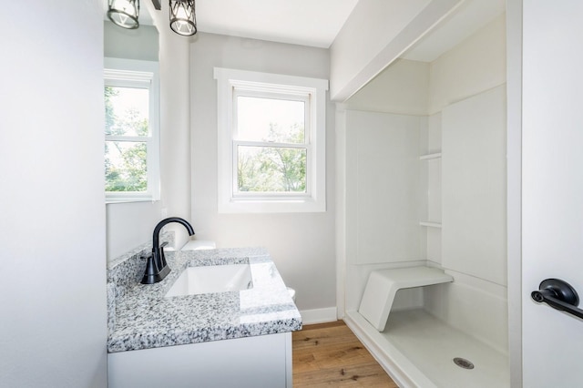 3811 E 30th St, Des Moines, IA 50317 - full bathroom with vanity, a shower, wood finished floors, and baseboards