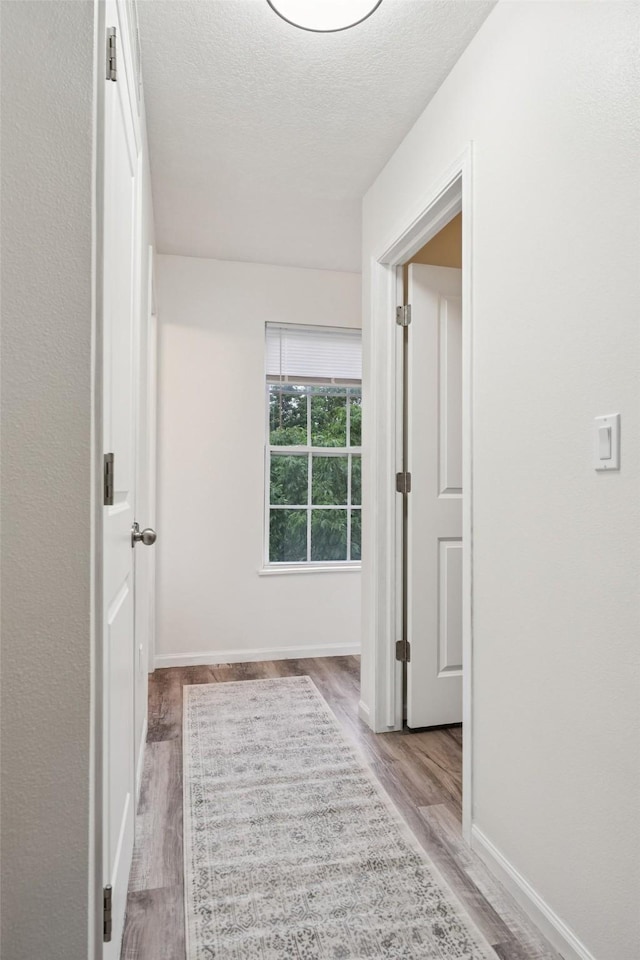 2150 NE 18th St Unit 101, Grimes, IA 50111 - corridor featuring wood finished floors, a textured ceiling, and baseboards