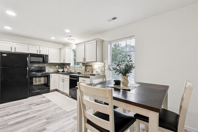 2150 NE 18th St Unit 101, Grimes, IA 50111 - kitchen with black appliances, dark countertops, decorative backsplash, light wood finished floors, and a sink