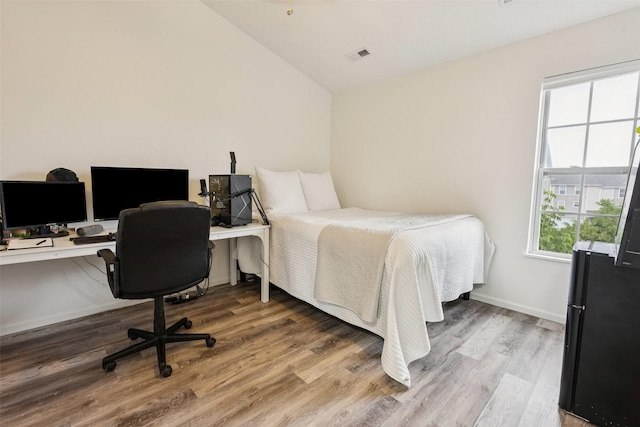2150 NE 18th St Unit 101, Grimes, IA 50111 - bedroom with freestanding refrigerator, vaulted ceiling, wood finished floors, an office area, and baseboards