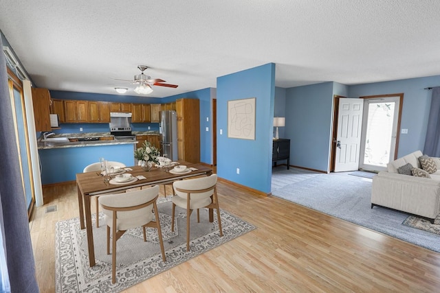 102 Jackson St, Pella, IA 50219 - dining room with a textured ceiling, ceiling fan, light wood finished floors, and baseboards
