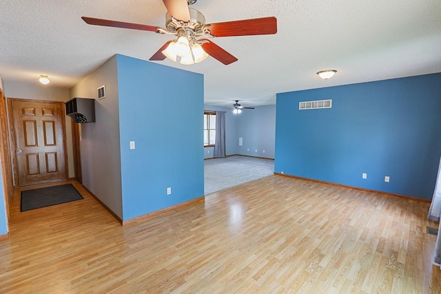 102 Jackson St, Pella, IA 50219 - spare room with ceiling fan, light wood finished floors, baseboards, and a textured ceiling