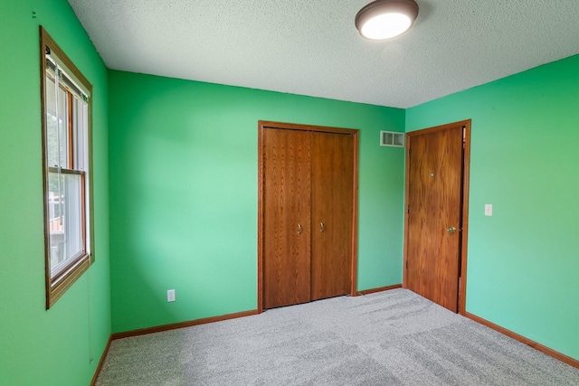 102 Jackson St, Pella, IA 50219 - unfurnished bedroom featuring a textured ceiling, a closet, carpet floors, and baseboards