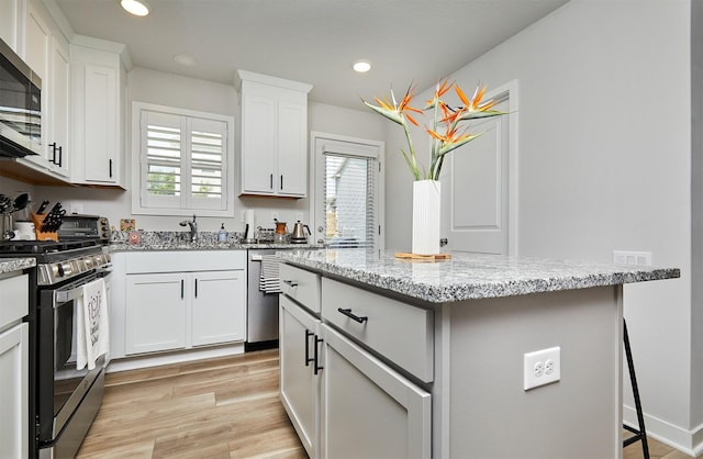 134 Aspen Dr, Norwalk, IA 50211 - kitchen with stainless steel appliances, plenty of natural light, a center island, recessed lighting, and light stone counters