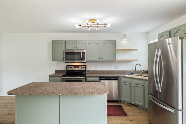 3605 Village Run Dr, Des Moines, IA 50317 - kitchen featuring stainless steel appliances, a sink, open shelves, green cabinetry, and wood finished floors