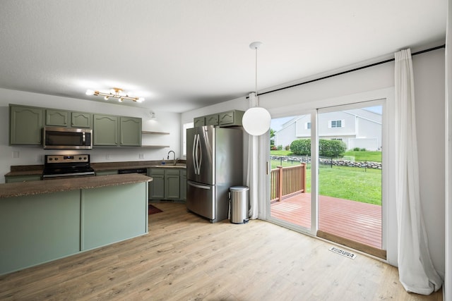 3605 Village Run Dr, Des Moines, IA 50317 - kitchen with stainless steel appliances, green cabinets, light wood-style floors, decorative light fixtures, and a sink