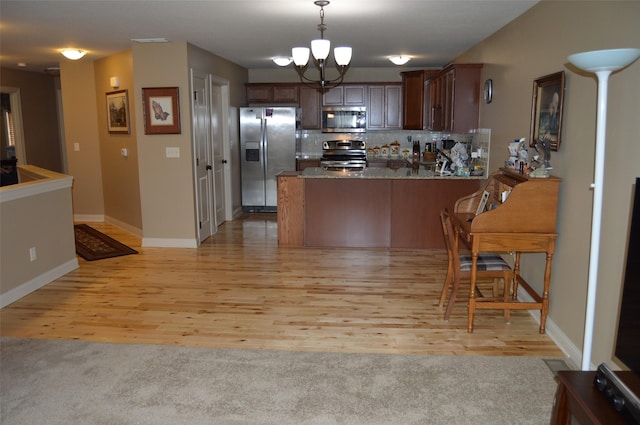 6029 Meacham Dr, Pleasant Hill, IA 50327 - kitchen with stainless steel appliances, a peninsula, a chandelier, light wood finished floors, and decorative light fixtures