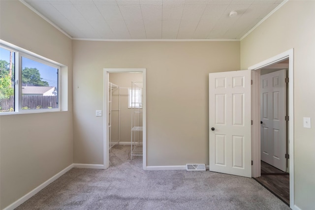 2336 E 13th St, Des Moines, IA 50316 - unfurnished bedroom featuring crown molding, carpet floors, a walk in closet, a closet, and baseboards