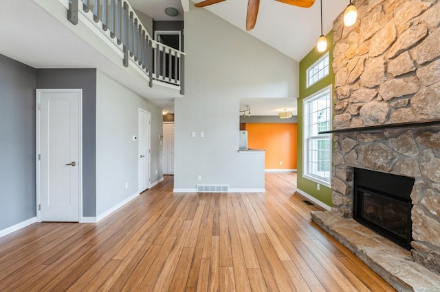 2405 81st Cir, Urbandale, IA 50322 - unfurnished living room with a high ceiling, wood finished floors, ceiling fan, and a fireplace