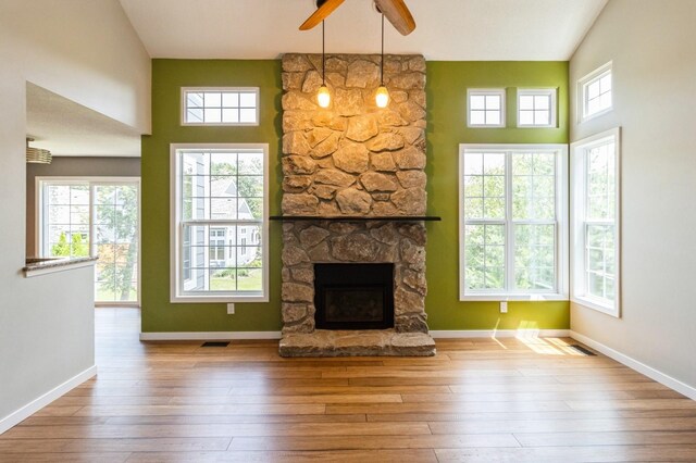 2405 81st Cir, Urbandale, IA 50322 - unfurnished living room featuring a ceiling fan, a stone fireplace, hardwood / wood-style floors, and a towering ceiling