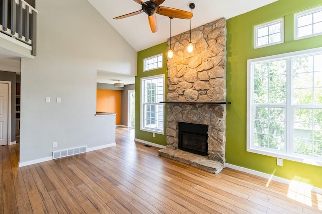 2405 81st Cir, Urbandale, IA 50322 - unfurnished living room with high vaulted ceiling, a ceiling fan, hardwood / wood-style flooring, and a stone fireplace