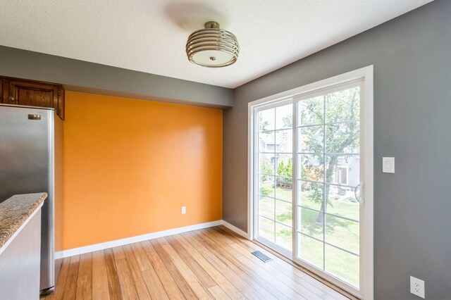 2405 81st Cir, Urbandale, IA 50322 - unfurnished dining area featuring light wood-type flooring and baseboards